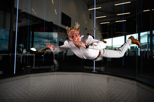 Kvinna i vit dräkt som flyger. Köp en 50 års present till en kvinna hos oss på Bodyflight.