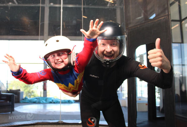 En flygande tjej som valt indoor skydiving bland inomhus aktiviteter barn.